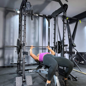 Woman performing bench press on power rack