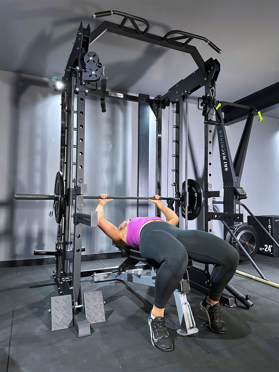 Woman performing bench press on power rack