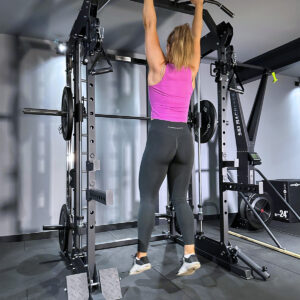 Woman doing pull ups row on home gym power rack