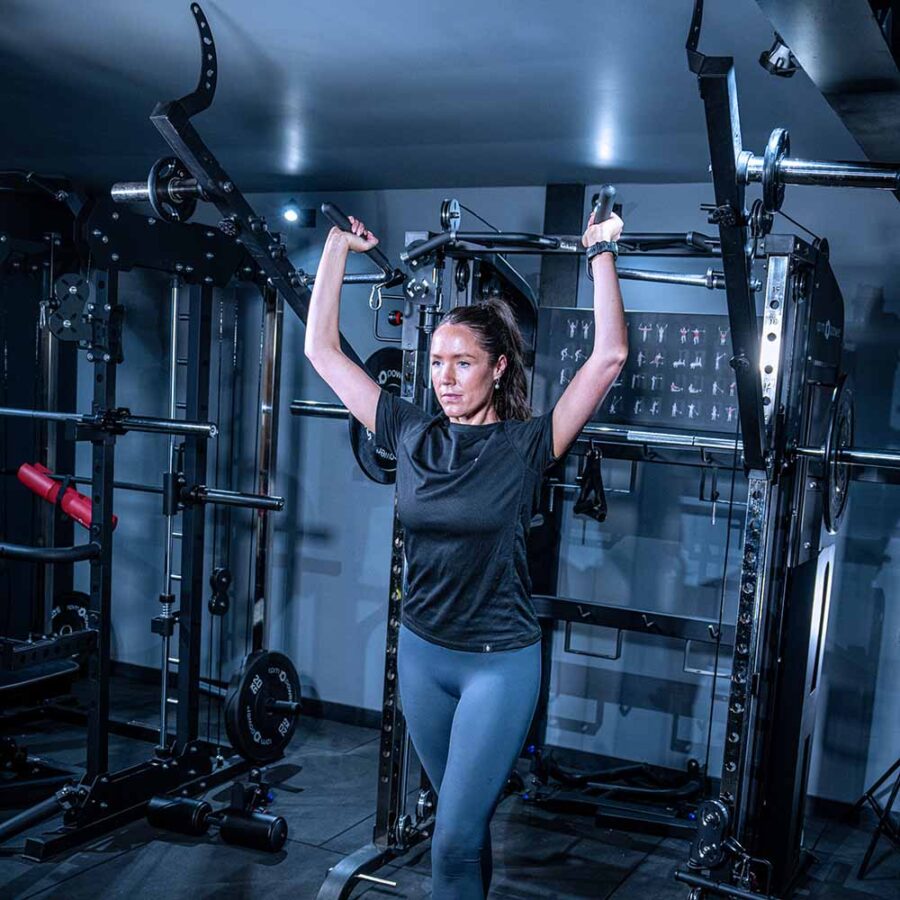 Woman using Multigym with Smith Bar, Weight Stack and Pull Up bar