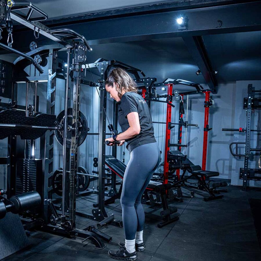 Woman using Multigym with Smith Bar, Weight Stack and Pull Up bar