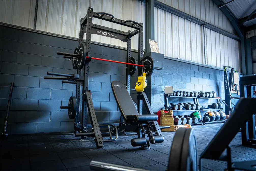 a rebel half rack, weight bench and barbell in a gym setting