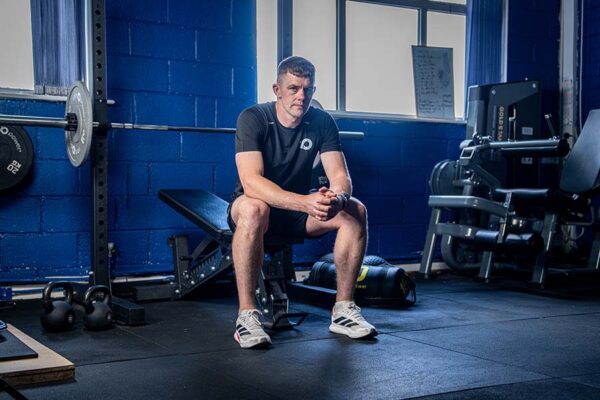 Ronan Maher sitting on a weight bench in a gym