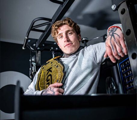 Ciarain Shanahan with his belt leaning against Kratos Multi-Gym