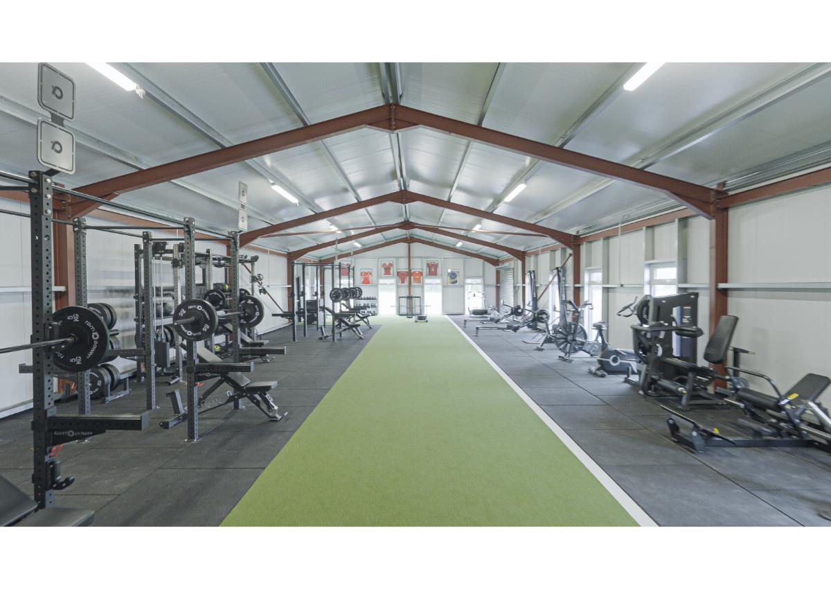 wide shot of full gym with green turf flooring and gym equipment