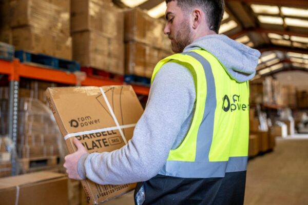 A man in a hi-vis vest holds a box