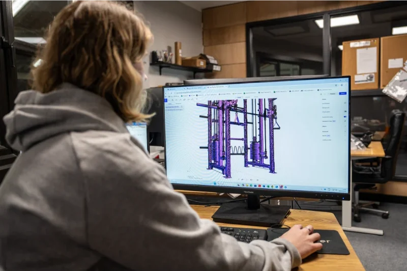 A woman using a computer with a 3D fitness equipment design