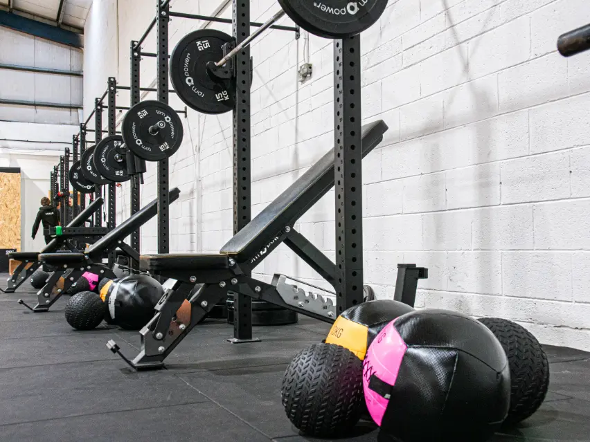 Wall balls beside a weight bench and wall-mounted gym rig