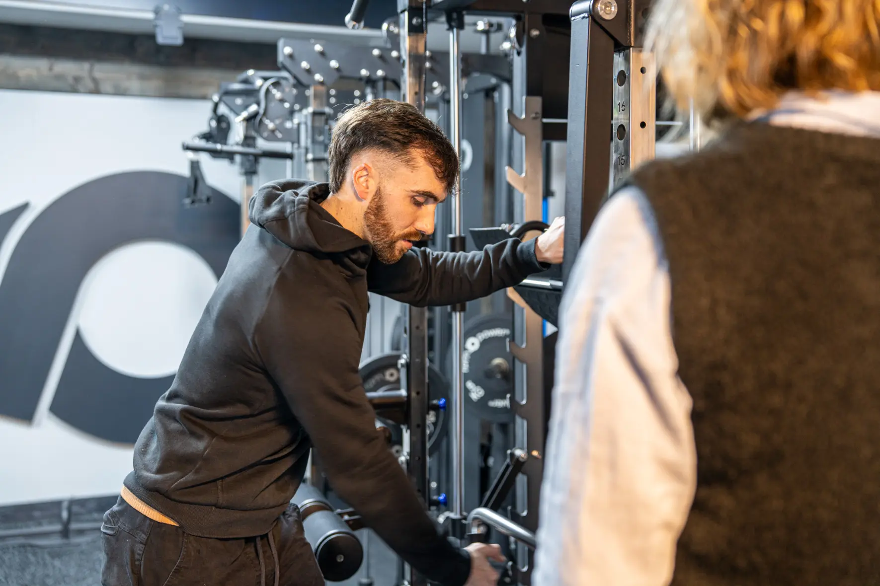 A man shows a woman how to use a multi-gym